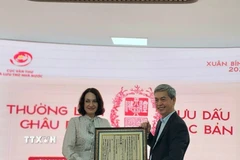 Cục trưởng Cục Văn thư và Lưu trữ nhà nước Đặng Thanh Tùng tặng bà Elena Bezdetko, Phu nhân Đại sứ Nga tại Việt Nam bản in dập từ Mộc bản về Quốc hiệu Việt Nam. (Ảnh: Chu Thanh Vân/TTXVN)