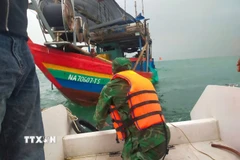 Lực lượng cứu nạn của Đồn Biên phòng Diễn Thành tiếp cận vị trí tàu cá bị chìm, đưa 3 ngư dân gặp nạn lên ca nô an toàn. (Ảnh: TTXVN phát)