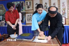 Du khách trải nghiệm in tranh dân gian Đông Hồ. (Ảnh: Thanh Thương/TTXVN)