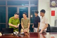 Khám xét đối tượng Chảo Duần Chình tại cơ quan Công an. (Ảnh: TTXVN phát)