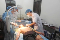 Các bác sỹ thăm khám vết thương cho ngư dân Đặng Văn Tắng. (Ảnh: TTXVN phát)