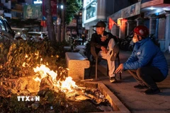 Người dân đốt lửa sưởi ấm trên hè phố. (Ảnh: Phạm Tuấn Anh/TTXVN)