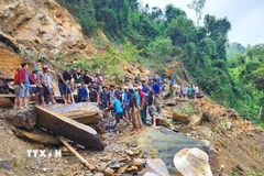 Người dân dùng xà beng, búa tạ phá nhỏ những tảng đá lớn tại điểm sạt lở trước khi kích nâng lên thanh trượt để dịch chuyển sang mép vực, tạo lối mở qua điểm sạt lở. (Ảnh: TTXVN phát)
