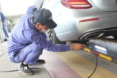 Nhân viên đăng kiểm thực hiện thao tác trong quy trình kiểm định khí thải. (Ảnh: Nguyễn Thắng/TTXVN)