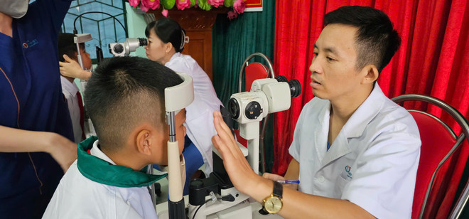 Bác sỹ Đàm Đức Long khám cho bé trai cận 10 độ. (Ảnh: PV/Vietnam+) be-trai.jpg