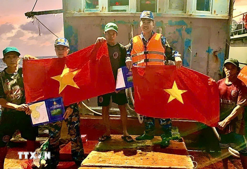 Cán bộ, chiến sỹ Vùng 2 Hải quân tuyên truyền, tặng cờ cho ngư dân trên biển. (Ảnh: TTXVN phát)