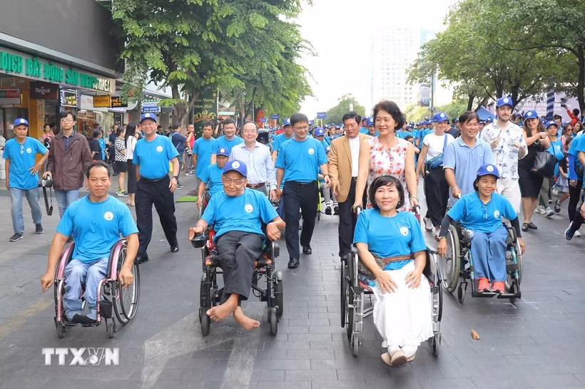 Thứ trưởng Bộ Y tế Nguyễn Thị Liên Hương và ông Nguyễn Mạnh Cường, Phó Chủ tịch Ủy ban Nhân dân Thành phố Hồ Chí Minh, cùng các đại biểu và người khuyết tật đi bộ đồng hành nhân Lễ kỷ niệm Ngày Người khuyết tật Việt Nam. (Ảnh: Thanh Vũ/TTXVN)