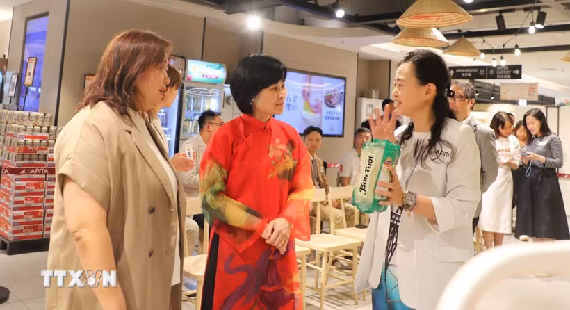 Đại diện siêu thị APITA giới thiệu món bún khô được người dân Hong Kong ưa chuộng. (Ảnh: Trần Thị Lê Anh/TTXVN)