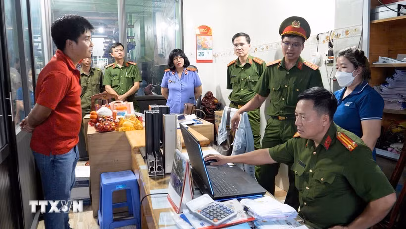 Lực lượng chức năng khám xét nơi làm việc của các bị can. (Ảnh: TTXVN phát)