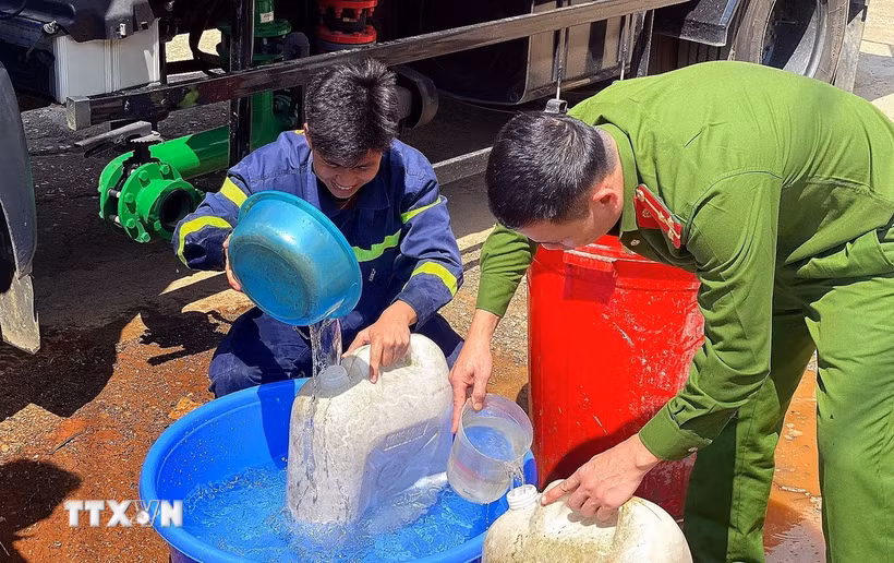Các chiến sỹ Phòng cháy chữa cháy cùng Công an xã Pà Cò hỗ trợ phân phát nước cho người dân địa phương. (Ảnh: Thanh Hải/TTXVN)