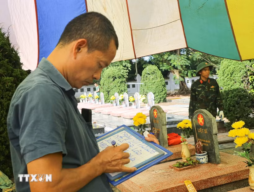 Lực lượng chức năng cẩn trọng ghi chép thông tin trong quá trình khai quật các phần mộ tại Nghĩa trang Liệt sỹ Độc Lập, xã Thanh Nưa. (Ảnh: Phan Quân/TTXVN)