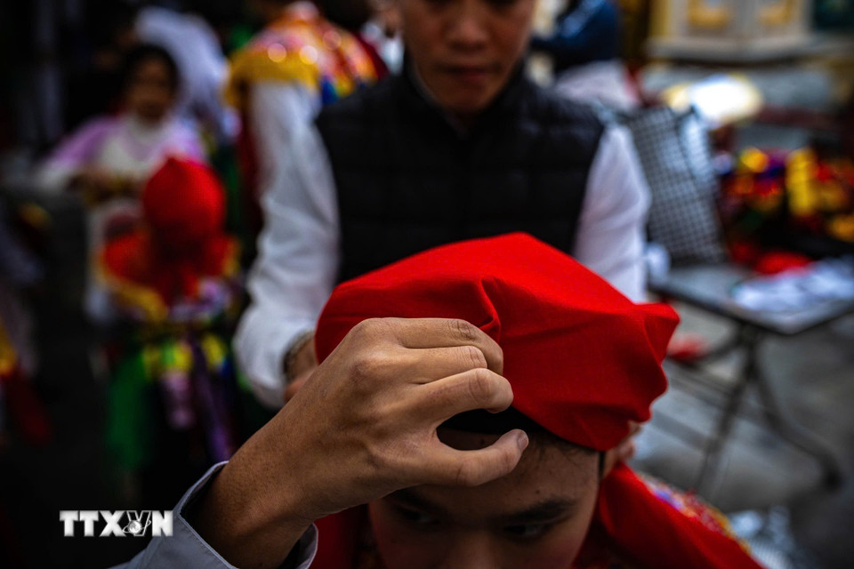 Giữ khăn để tạo ra hình dáng đặc trưng giống mỏ quạ trước khi thắt múi ở gáy, thường được sử dụng trong các trang phục truyền thống hoặc trong những dịp lễ hội đặc biệt. (Ảnh: Phạm Tuấn Anh/TTXVN)