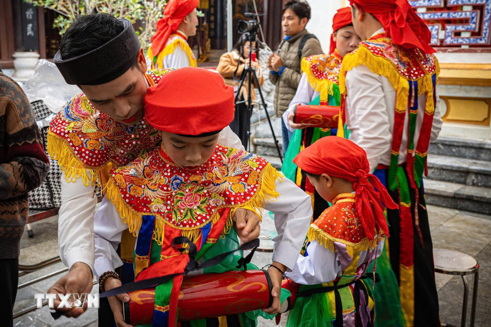Thành viên CLB trống bồng Triều Khúc hướng dẫn, chuẩn bị trống bồng cho các em nhỏ trước khi tham gia biểu diễn. (Ảnh: Phạm Tuấn Anh /TTXVN)