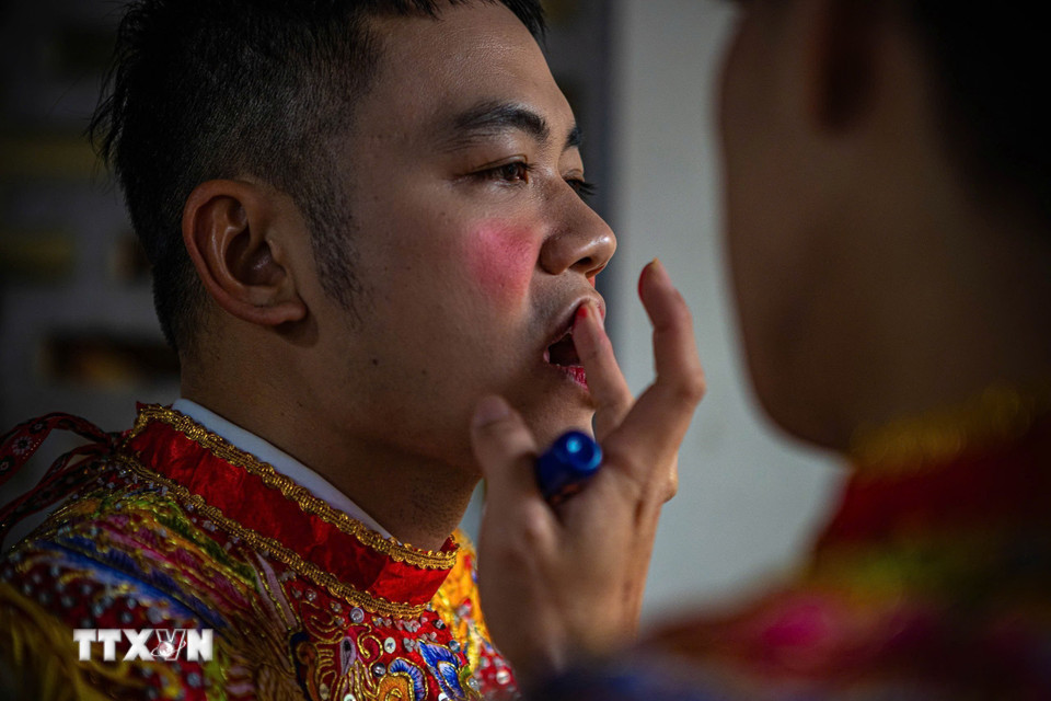 Thành viên CLB trống bồng Triều Khúc đánh má phấn, tô son... hóa trang giả gái chuẩn bị cho biểu diễn múa bồng. (Ảnh: Phạm Tuấn Anh/TTXVN