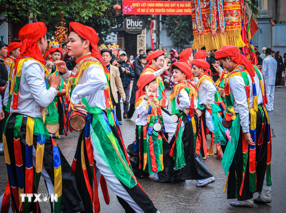 Các trai làng đóng giả làm con gái, má phấn, môi son, đầu chít khăn mỏ quạ, váy nhiễu màu đen với những dải màu ngũ sắc biểu diễn điệu múa "Con đĩ đánh bồng" trong lễ hội. (Ảnh: Hoàng Hiếu/TTXVN)
