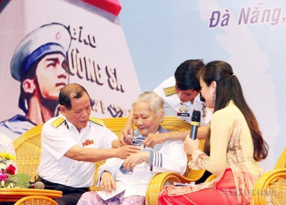 Bà Lê Thị Muộn, mẹ của Liệt sỹ Phan Văn Sự, người đã hy sinh anh dũng trong trận chiến bảo vệ Gạc Ma năm 1988, mặc chiếc áo - kỷ vật duy nhất còn lại của người con trai, tại chương trình giao lưu “Hướng về Trường Sa thân yêu,” ngày 14/3/2013. (Ảnh: Trần Lê Lâm/TTXVN)