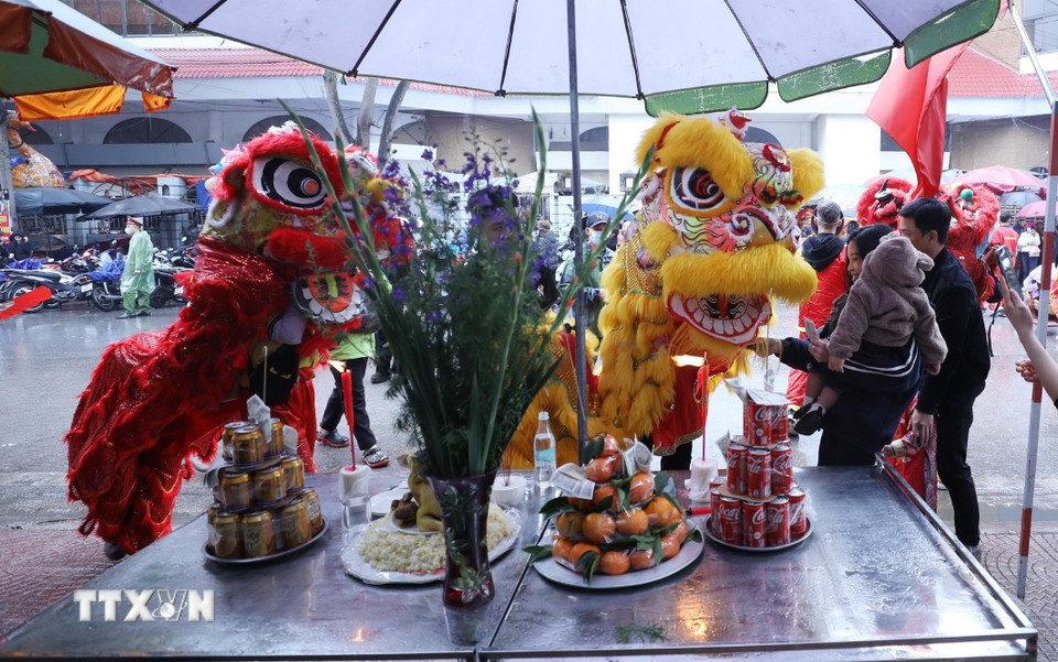 Đội lân sư rồng ghé qua mâm lễ của các gia đình chúc làm ăn đắc lộc. (Ảnh: Anh Tuấn/TTXVN)