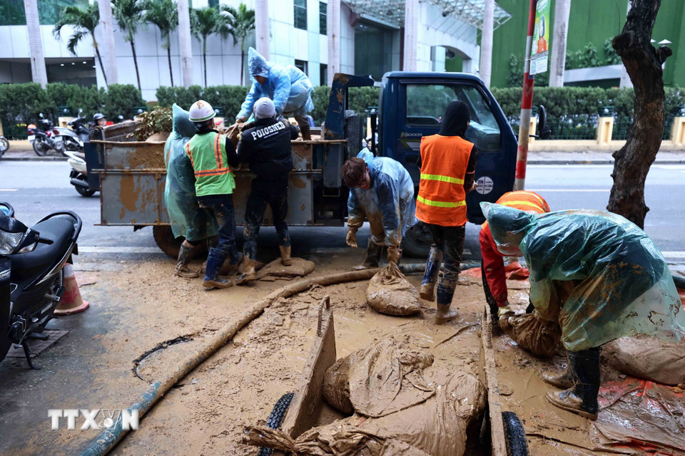 Công nhân Công ty vệ sinh môi trường đô thị Hà Nội tiếp tục dọn dẹp những vật dụng dùng trong lúc xử lý bùn nhão phun trào. (Ảnh: An Đăng/TTXVN)