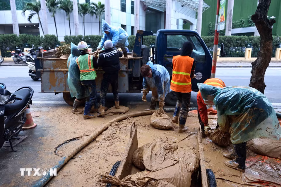 Công nhân Công ty vệ sinh môi trường đô thị Hà Nội tiếp tục dọn dẹp những vật dụng dùng trong lúc xử lý bùn nhão phun trào. (Ảnh: An Đăng/TTXVN)