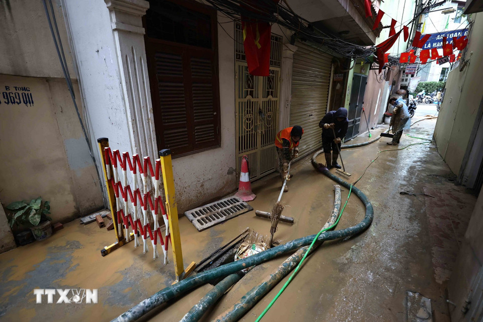 Công nhân Công ty vệ sinh môi trường đô thị Hà Nội và người dân đang khẩn trương làm sạch ngõ số 7 Giang Văn Minh để đưa cuộc sống sinh hoạt lại bình thường. (Ảnh: An Đăng/TTXVN)