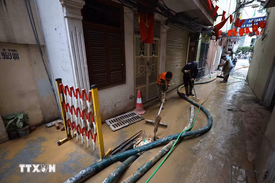 Công nhân Công ty vệ sinh môi trường đô thị Hà Nội và người dân đang khẩn trương làm sạch ngõ số 7 Giang Văn Minh để đưa cuộc sống sinh hoạt lại bình thường. (Ảnh: An Đăng/TTXVN)