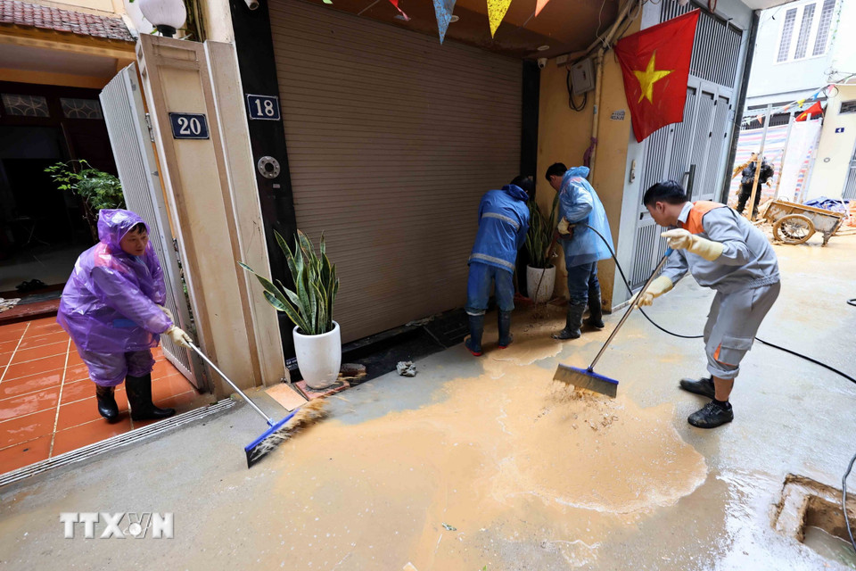 Công nhân Công ty vệ sinh môi trường đô thị Hà Nội và người dân đang khẩn trương làm sạch ngõ số 7 Giang Văn Minh để đưa cuộc sống sinh hoạt lại bình thường. (Ảnh: An Đăng/TTXVN)