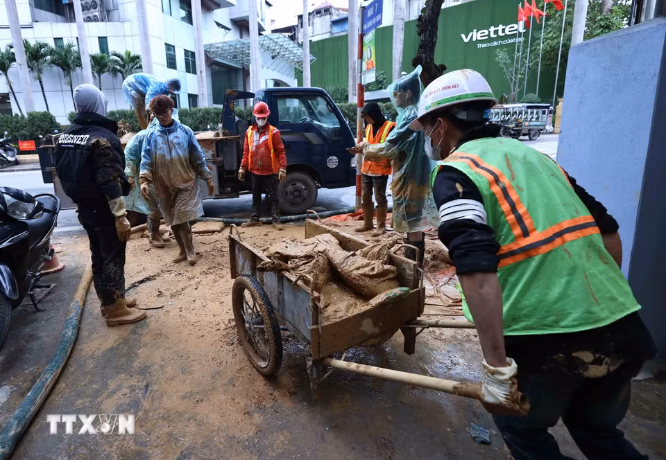 Công nhân Công ty vệ sinh môi trường đô thị Hà Nội tiếp tục dọn dẹp những vật dụng dùng trong lúc xử lý bùn nhão phun trào. (Ảnh: An Đăng/TTXVN)
