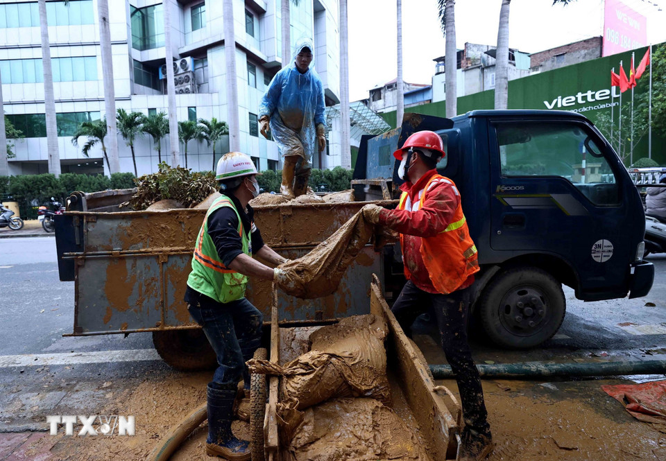 Công nhân Công ty vệ sinh môi trường đô thị Hà Nội tiếp tục dọn dẹp những vật dụng dùng trong lúc xử lý bùn nhão phun trào. (Ảnh: An Đăng/TTXVN)