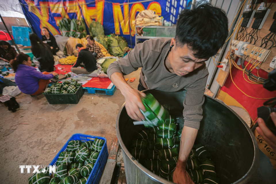 Người dân Tranh Khúc tất bật mỗi người một công đoạn từ làm lá, gói bánh, xếp bánh vào nồi đun điện. (Ảnh: Hoàng Hiếu/TTXVN)