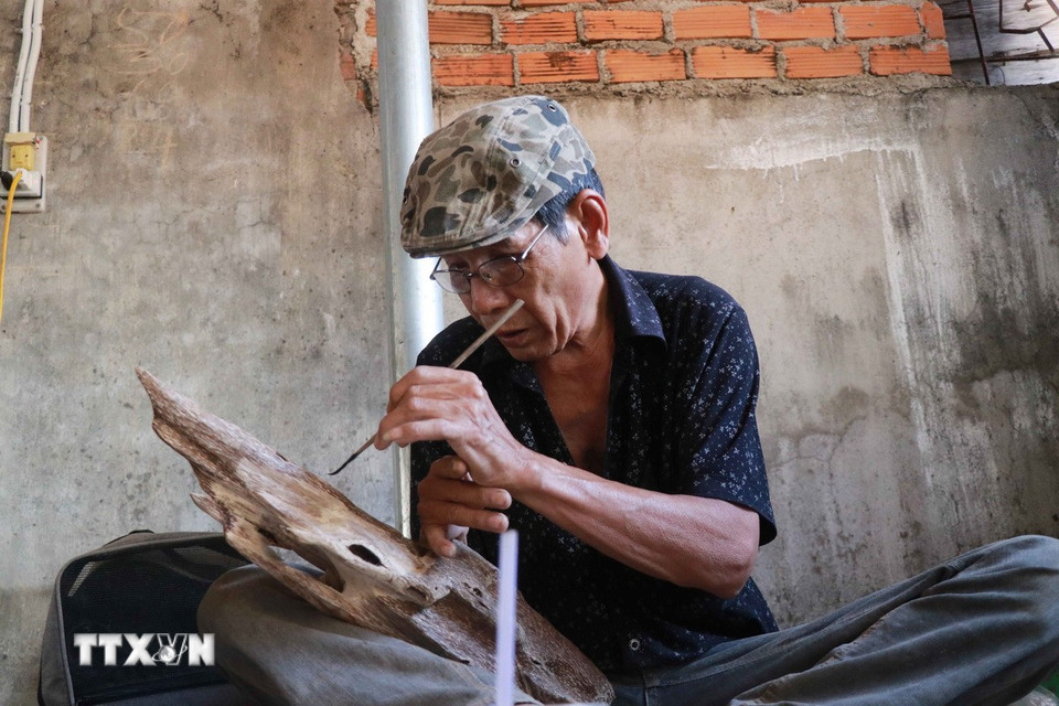 Ông Lê Long gọt tỉa một sản phẩm trầm cảnh mỹ nghệ. (Ảnh: Đặng Tuấn/TTXVN)