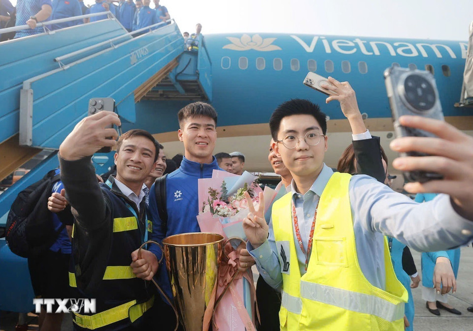 Nhân viên hàng không chụp ảnh selfie cùng Duy Mạnh và cúp vô địch. (Ảnh: Minh Quyết/TTXVN)