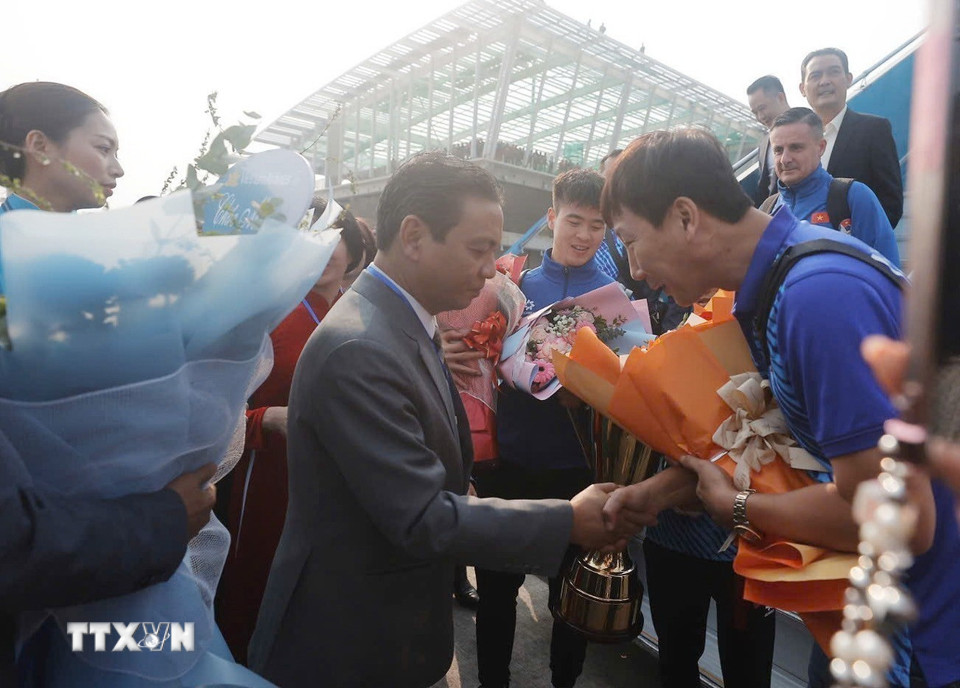 Thứ trưởng Bộ Văn hóa, Thể thao và Du lịch Hoàng Đạo Cương đón, tặng hoa chúc mừng HLV Kim Sang-sik và đội tuyển tại chân cầu thang máy bay. (Ảnh: Minh Quyết/TTXVN)