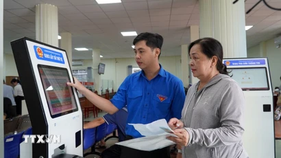 Thanh niên tình nguyện phường Rạch Giá, An Giang, hướng dẫn người dân đăng ký giải quyết thủ tục hành chính trên hệ thống. (Ảnh: Văn Sĩ/TTXVN)