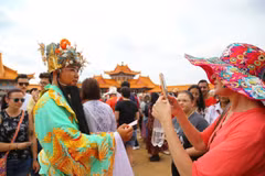 Du khách thích thú chụp ảnh lưu niệm cùng nhân vật Thần Tài trong dân gian của người châu Á. (Ảnh: Hồng Minh/TTXVN)