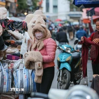 Người lao động, bán hàng trên phố che chắn kỹ chống rét. (Ảnh: Hoàng Hiếu/TTXVN)
