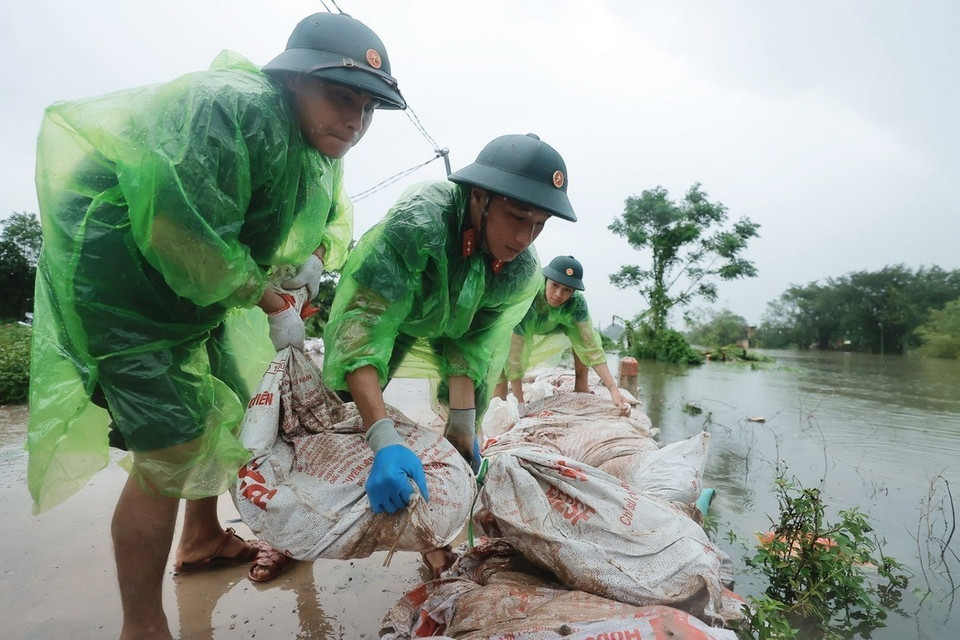 Cán bộ, chiến sỹ Trung đoàn 102 hỗ trợ người dân đắp bao tải đất gia cố đê sông Tích. (Ảnh: Minh Quyết/TTXVN)