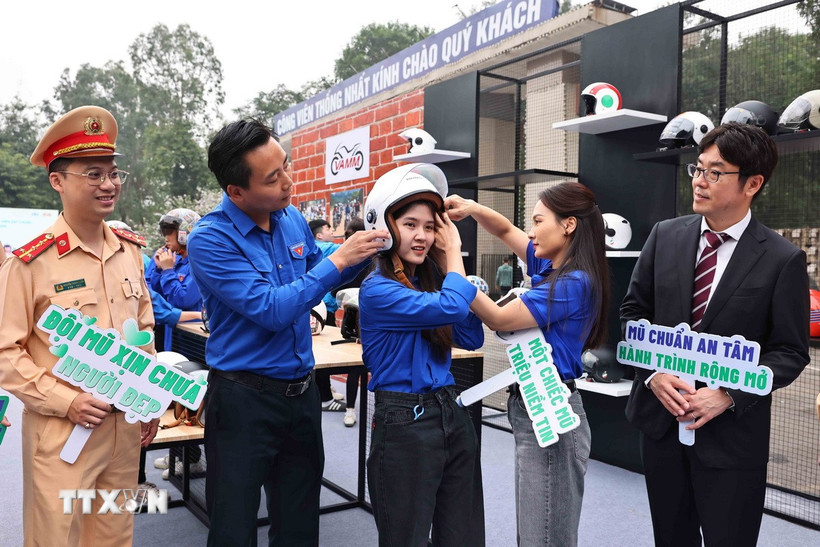 Hướng dẫn đội mũ để lái xe an toàn khi tham gia giao thông. (Ảnh: Minh Đức/TTXVN)