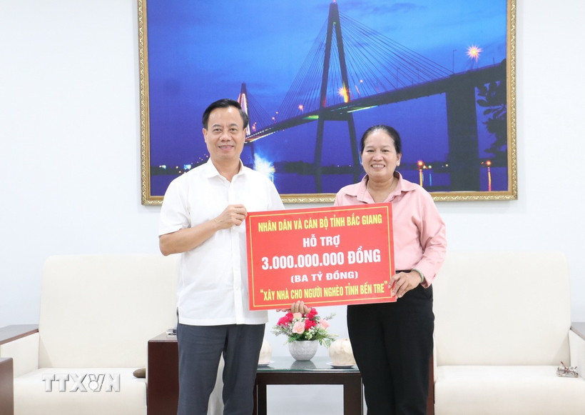 Chủ tịch Ủy ban Mặt trận Tổ quốc Việt Nam tỉnh Bắc Giang Đinh Đức Cảnh trao tặng Ủy ban Mặt trận Tổ quốc Việt Nam tỉnh Bến Tre bảng tượng trưng 3 tỷ đồng, để xây dựng 50 căn nhà Đại đoàn kết cho các hộ khó khăn về nhà ở tại tỉnh Bến Tre. (Ảnh: Chương Đài/TTXVN)