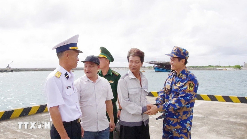 Ngư dân Tiêu Viết Bút (thứ 2 bên phải sang) bắt tay tạm biệt cán bộ, chiến sỹ trên đảo Trường Sa trước khi trở lại tàu cá. (Ảnh: TTXVN phát)