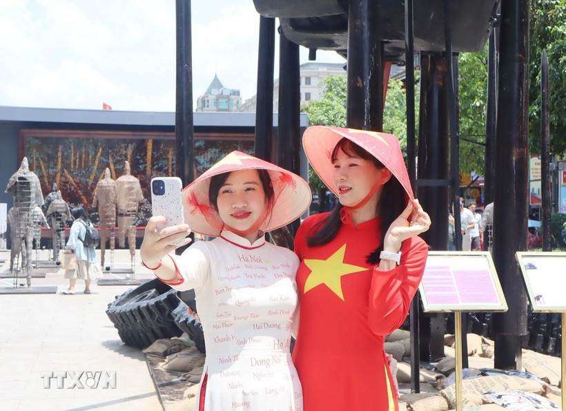 Người dân diện áo dài truyền thống, cờ đỏ sao vàng ghi lại những khoảnh khắc đẹp trong dịp lễ kỷ niệm. (Ảnh: Thu Hương/TTXVN)