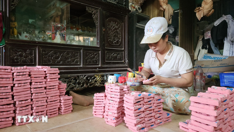 Trang trí tượng Tam vị Táo quân phù hợp thị hiếu khách hàng dịp Tết. (Ảnh: Võ Văn Dũng/TTXVN)