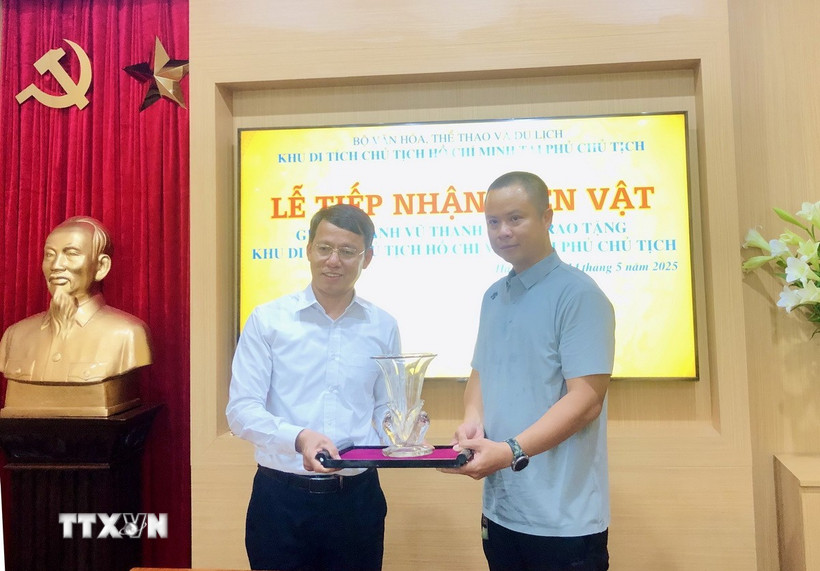 Phó Giám đốc Khu Di tích Chủ tịch Hồ Chí Minh tại Phủ Chủ tịch Nguyễn Văn Dương tiếp nhận lọ hoa do gia đình ông Vũ Thanh Tùng trao tặng. (Ảnh: Phương Lan/TTXVN)