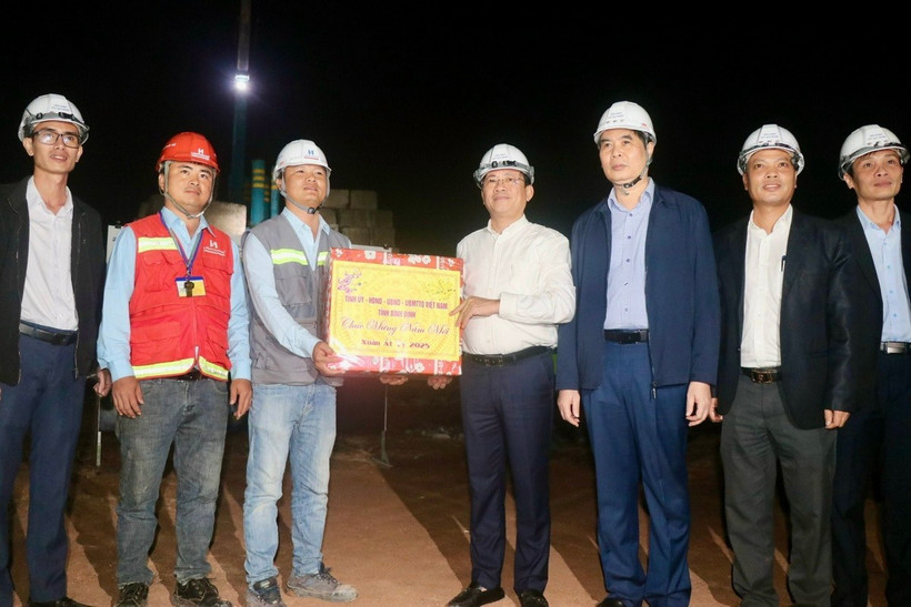 Chủ tịch Ủy ban Nhân dân tỉnh Bình Định Phạm Anh Tuấn tặng quà cho công nhân làm xuyên đêm tại công trường. (Ảnh: Sỹ Thắng/TTXVN)