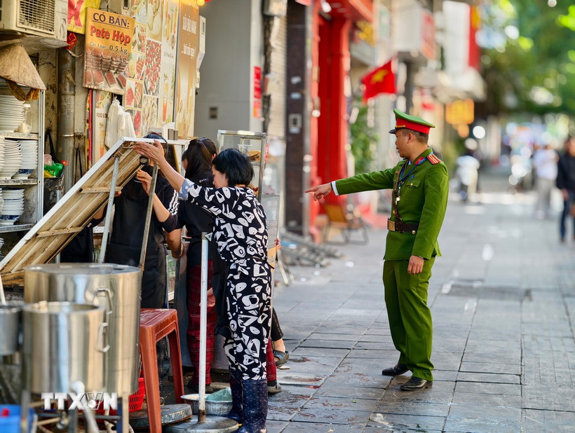 Lực lượng chức năng đi vận động hộ kinh doanh không lấn chiếm vỉa hè tại phố Phan Chu Trinh, phường Cửa Nam. (Ảnh: Quốc Lũy/TTXVN)