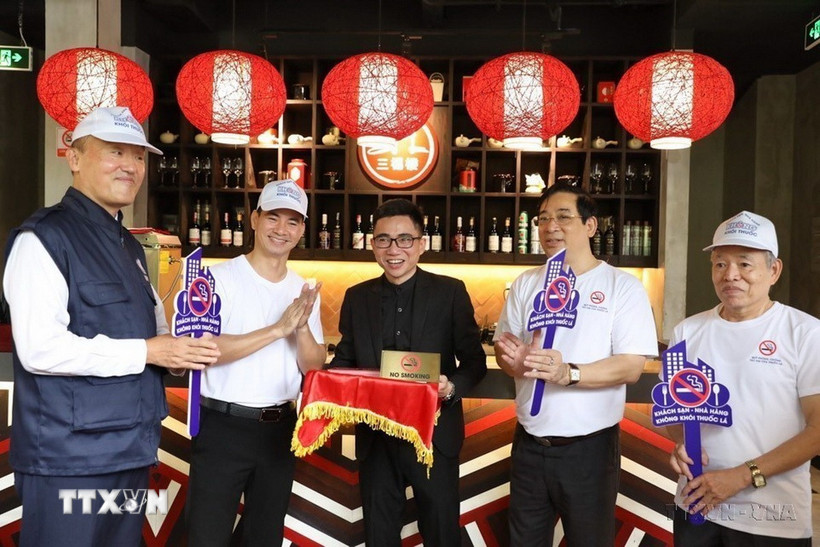 Đại biểu tham gia gắn biển cấm hút thuốc lá tại một số khách sạn, nhà hàng ở Hà Nội trong Lễ phát động Chiến dịch xây dựng khách sạn, nhà hàng không khói thuốc (năm 2021). (Ảnh: Minh Quyết/TTXVN)