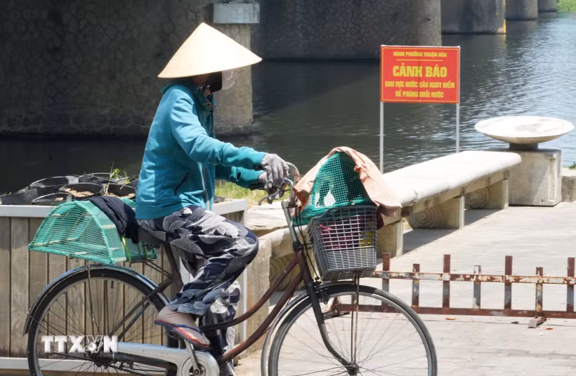 Người dân mặc kín đồ bảo hộ chống nắng nóng khi mưu sinh ở bờ Nam sông Hương, phường Thuận Hóa, thành phố Huế. (Ảnh: Nguyên Lý/TTXVN)