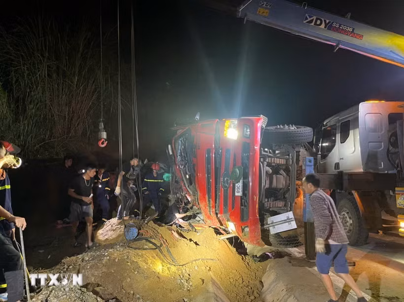 Cabin xe tải bị biến dạng, cùng trời tối và thời tiết có sương mù khiến công tác cứu nạn, cứu hộ 2 nạn nhân mắc kẹt gặp không ít khó khăn. (Ảnh: TTXVN phát)
