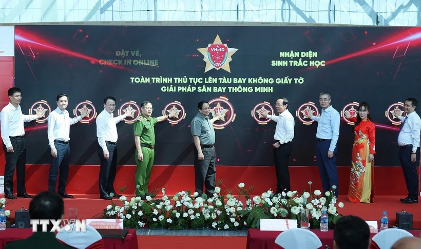 Thủ tướng Phạm Minh Chính và các đại biểu bấm nút triển khai giải pháp ứng dụng định danh, xác thực điện tử và nhận diện sinh trắc học phục vụ thủ tục lên tàu bay. (Ảnh: Dương Giang/TTXVN)