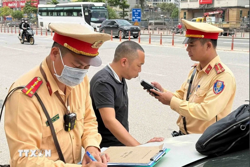 Cán bộ, chiến sỹ đội Cảnh sát Giao thông số 6 kiểm tra nồng độ cồn đối với tài xế xe khách. (Ảnh: Phạm Kiên/TTXVN)