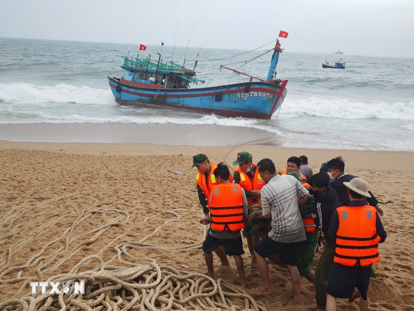 Lực lượng chức năng và người dân địa phương hỗ trợ cứu nạn tàu cá BĐ 97820 TS. (Ảnh: TTXVN phát)